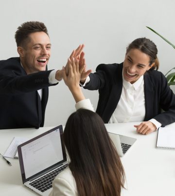 Excited millennial office team giving high five together, business people celebrating good teamwork result or common goal achievement, expressing unity, good corporate relations, teambuilding concept